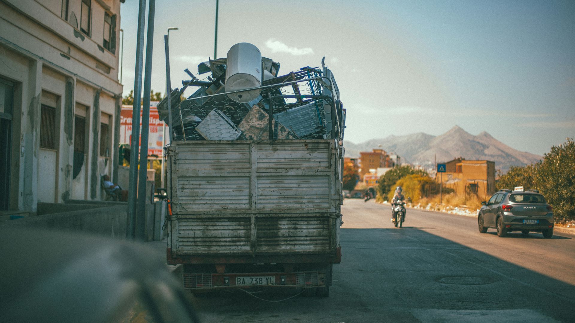 A truck loaded with scrap metal on a sunny street in Palermo, Italy